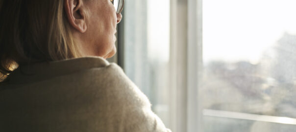 Woman with depression seen looking out a window